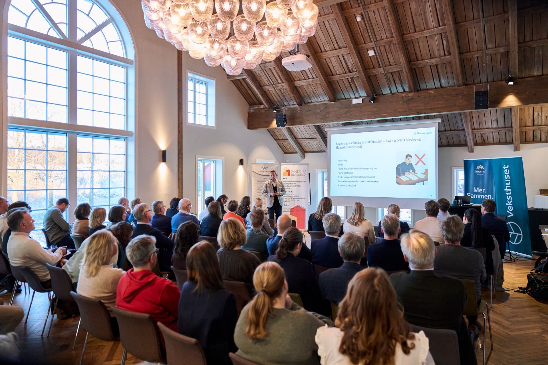 Fullsatt sal med publikum som følger et foredrag på storskjerm